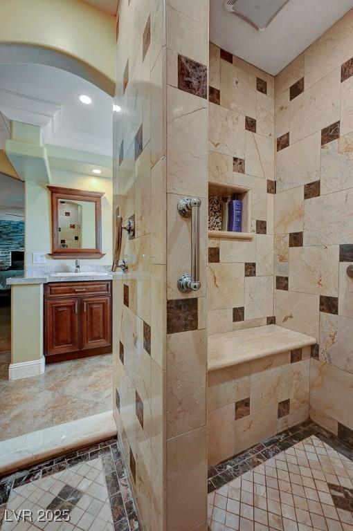 bathroom with a tile shower and vanity