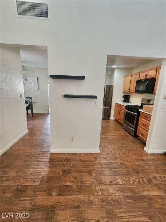 kitchen featuring dark hardwood / wood-style flooring, ceiling fan, and appliances with stainless steel finishes