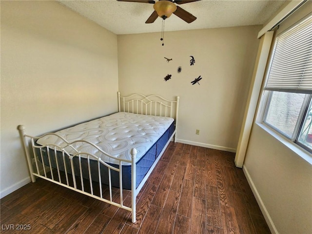 bedroom with ceiling fan, dark hardwood / wood-style floors, and a textured ceiling