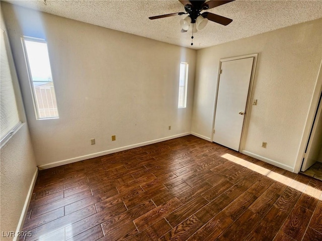 spare room with ceiling fan, a textured ceiling, dark hardwood / wood-style floors, and a healthy amount of sunlight