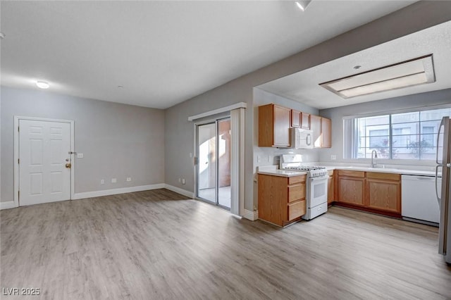 kitchen featuring white appliances, sink, and light wood-type flooring