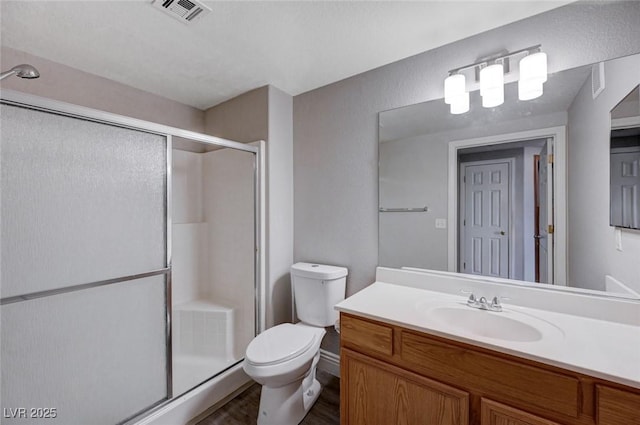 bathroom featuring vanity, an enclosed shower, and toilet