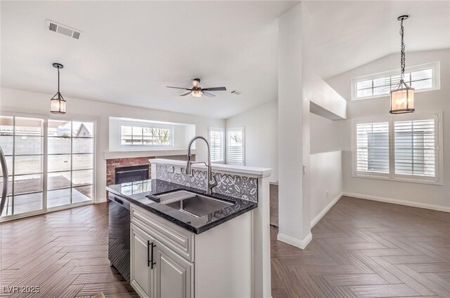 kitchen with white cabinetry, dark parquet flooring, sink, and a center island with sink