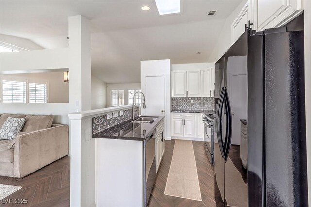 kitchen with dark parquet flooring, black appliances, sink, and white cabinets