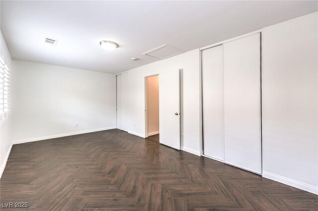 unfurnished bedroom with a closet and dark parquet floors