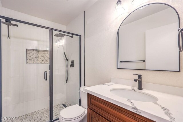 bathroom featuring vanity, a shower with shower door, and toilet