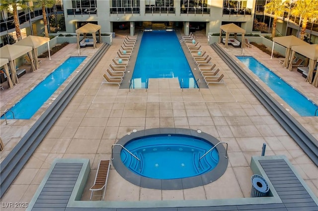 view of swimming pool featuring a community hot tub and a patio