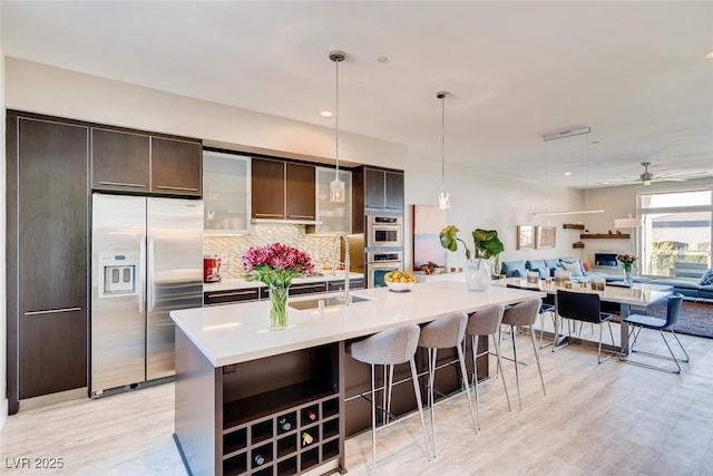 kitchen with a kitchen island with sink, decorative light fixtures, dark brown cabinetry, and appliances with stainless steel finishes