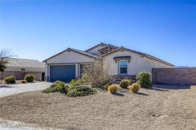 view of front of property with stucco siding, decorative driveway, stone siding, fence, and an attached garage