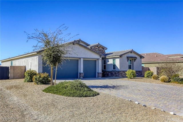 view of front facade with a tiled roof, stucco siding, decorative driveway, a garage, and stone siding