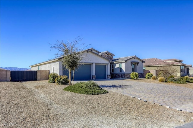 view of front facade with decorative driveway, a tile roof, an attached garage, and stucco siding