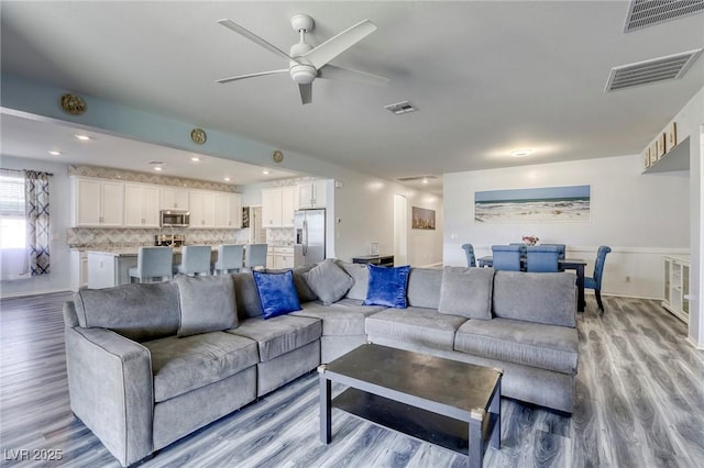 living room featuring a ceiling fan, wood finished floors, and visible vents