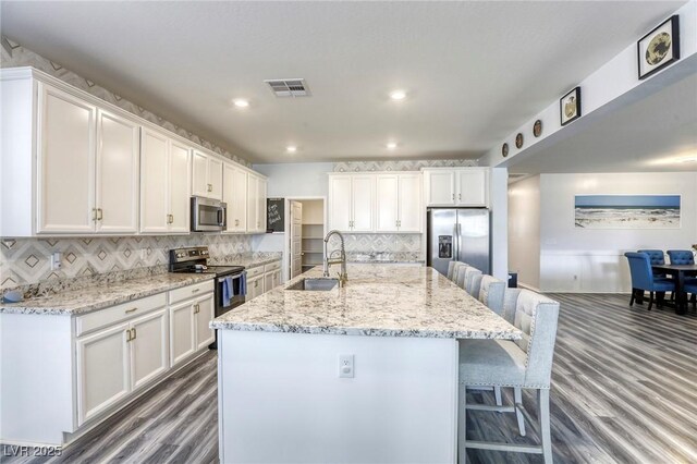 kitchen featuring white cabinetry, an island with sink, appliances with stainless steel finishes, and sink