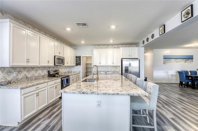 kitchen with a sink, visible vents, appliances with stainless steel finishes, and white cabinetry