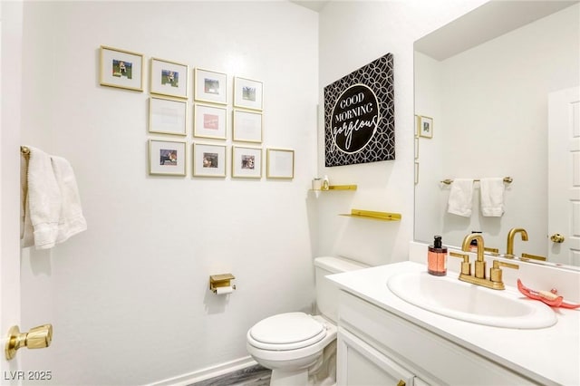 bathroom with baseboards, toilet, and vanity