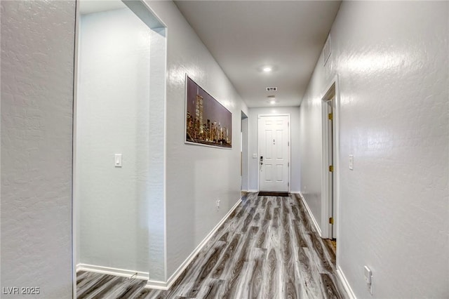 hallway with wood finished floors, baseboards, and a textured wall