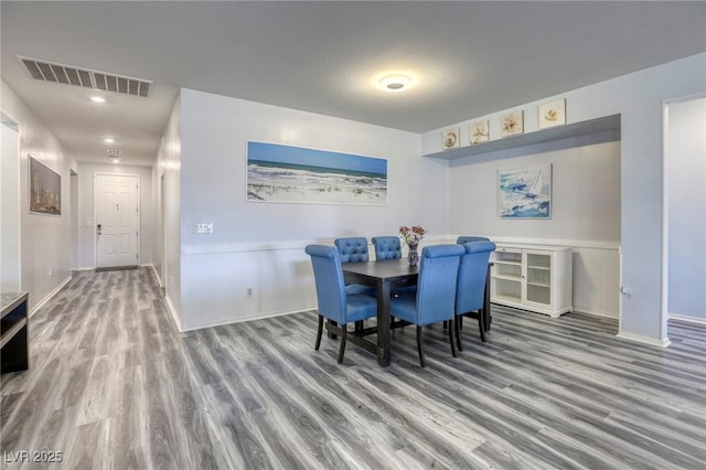 dining area with visible vents, a wainscoted wall, and wood finished floors