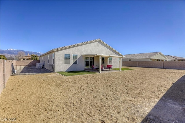 back of property with a patio area, a mountain view, a fenced backyard, and stucco siding