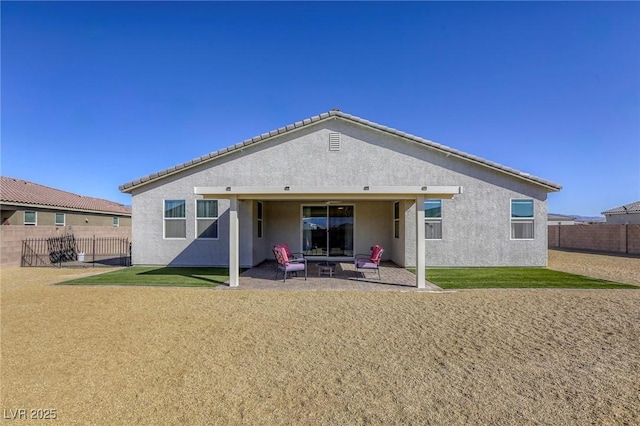 rear view of house featuring stucco siding, a patio, and fence