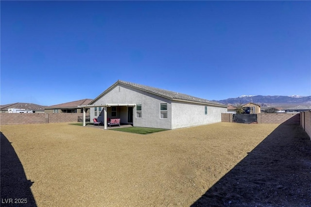 exterior space with stucco siding, a mountain view, a lawn, and a fenced backyard