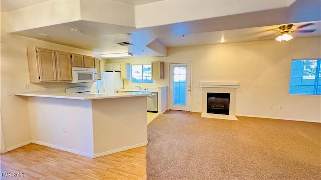 kitchen with white appliances, light carpet, kitchen peninsula, a tile fireplace, and ceiling fan