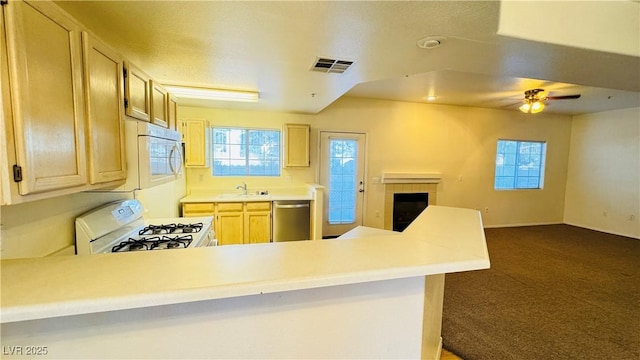 kitchen featuring white appliances, a fireplace, kitchen peninsula, and light brown cabinetry