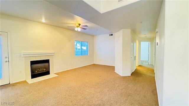 unfurnished living room with ceiling fan, light carpet, and a tile fireplace