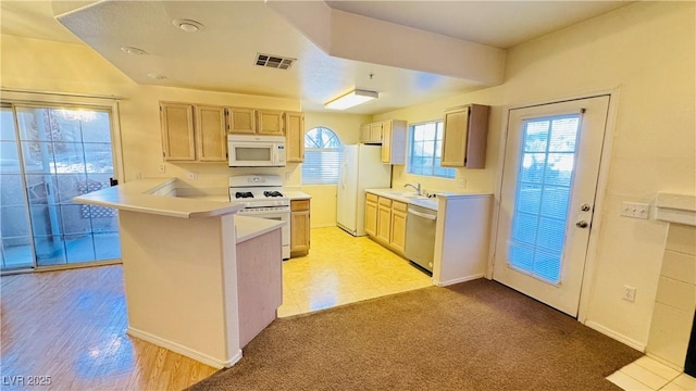 kitchen with light brown cabinetry, sink, kitchen peninsula, light carpet, and white appliances