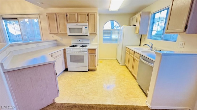 kitchen with white appliances, light brown cabinetry, and sink