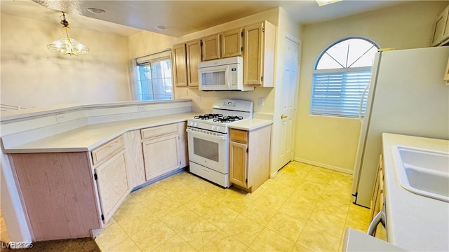 kitchen featuring pendant lighting, white appliances, and a chandelier