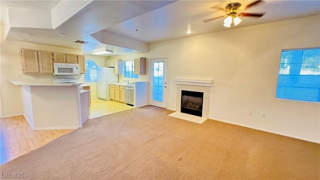 unfurnished living room featuring ceiling fan, light carpet, and a fireplace