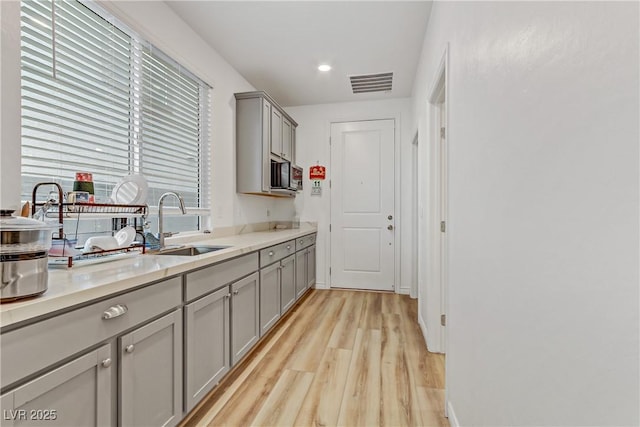 kitchen with gray cabinets, sink, and light hardwood / wood-style floors