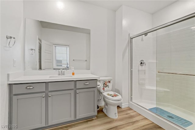 bathroom featuring wood-type flooring, toilet, a shower with door, and vanity