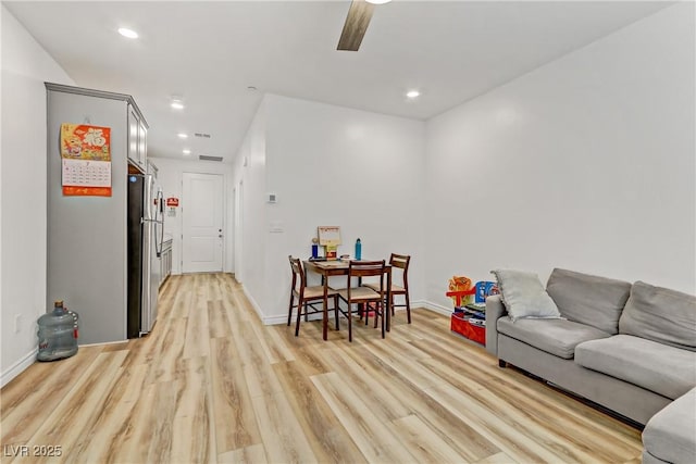 living room with light hardwood / wood-style flooring and ceiling fan