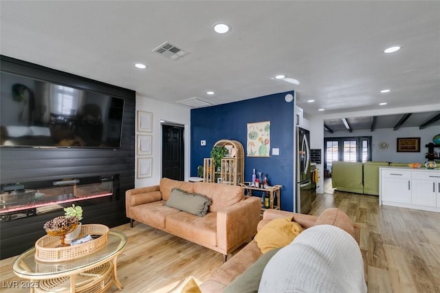 living room featuring beamed ceiling and light wood-type flooring