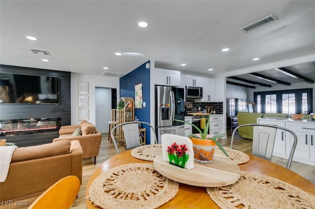 dining room featuring beamed ceiling and light wood-type flooring