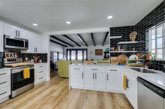 kitchen with sink, white cabinets, decorative backsplash, light hardwood / wood-style floors, and stainless steel appliances