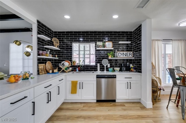 kitchen featuring tasteful backsplash, dishwasher, sink, white cabinets, and light hardwood / wood-style flooring