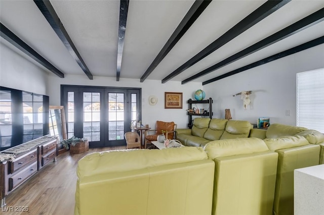 living room with beam ceiling, light wood-type flooring, and french doors