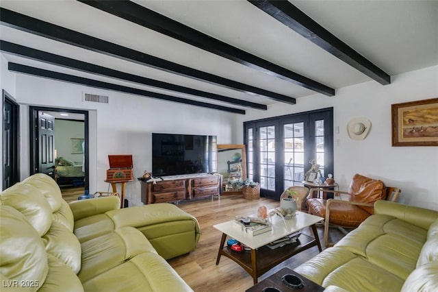 living room featuring french doors, beamed ceiling, and light wood-type flooring