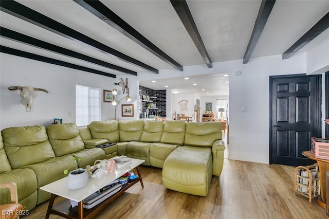 living room with beam ceiling, a healthy amount of sunlight, and light wood-type flooring