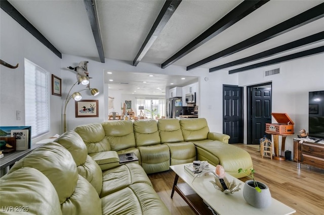 living room featuring beam ceiling and light hardwood / wood-style flooring