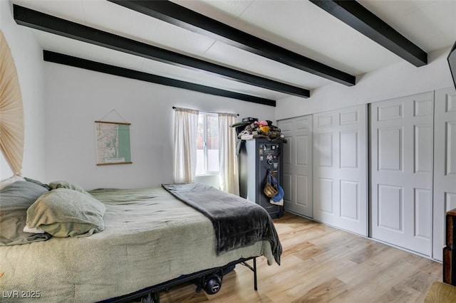 bedroom featuring beamed ceiling, a closet, and light hardwood / wood-style flooring