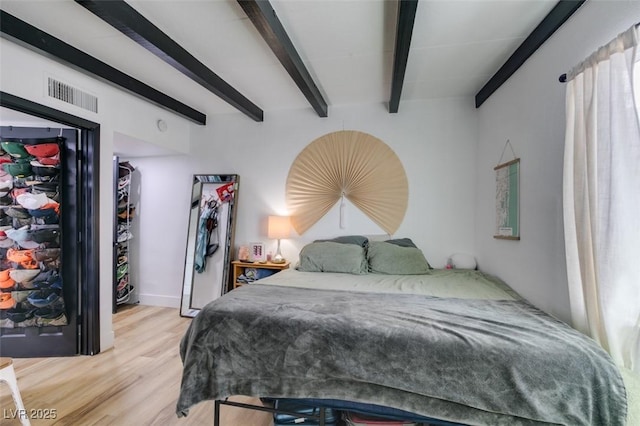 bedroom with beam ceiling and light wood-type flooring