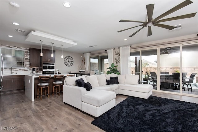 living area with recessed lighting, visible vents, ceiling fan, and light wood-style flooring