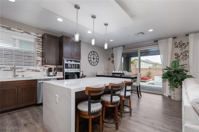 kitchen with visible vents, wood finished floors, light countertops, stainless steel appliances, and a sink