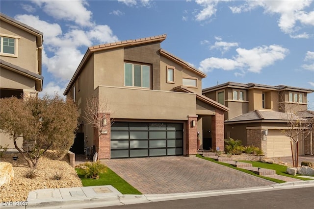 view of front of home featuring decorative driveway, an attached garage, and stucco siding