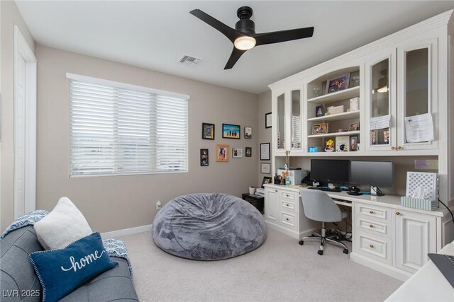 carpeted home office featuring built in desk and ceiling fan