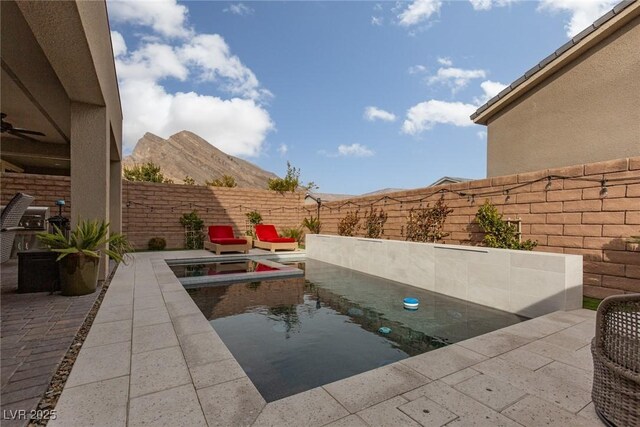 view of swimming pool with a patio, a mountain view, and ceiling fan