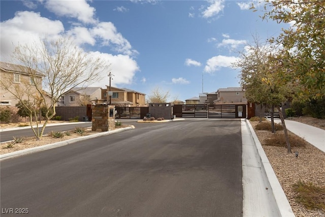 view of road featuring curbs, a gated entry, a residential view, and a gate